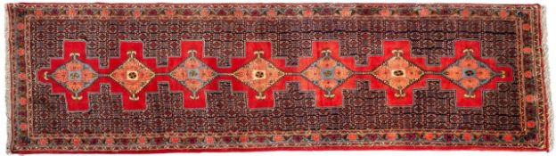 A Senneh runner, the rose field with a row of seven hooked lozenge medallions with palmette designs,