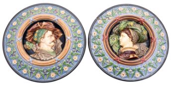 A pair of German majolica roundels moulded in high relief with a nobleman and noblewoman within a