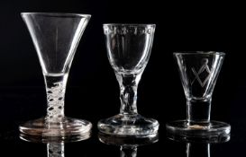 Three English firing glasses one with trumpet shaped bowl on a short single series opaque twist