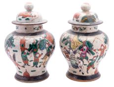 A pair of Chinese crackle ware baluster vases and covers enamelled with warriors in combat,