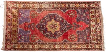 A Turkish rug, the plum field with a central lilac shaped lozenge pole medallion,