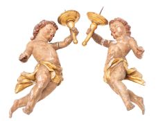 A pair of Continental carved, painted and parcel giltwood wall appliques modelled as amorini,