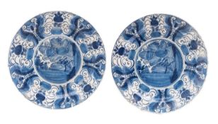 A pair of Dutch Delft plates each painted in blue with stylised flowers and foliage, 30cm diameter,