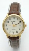 A Timex Indiglo Ladies Quartz Watch. Brown leather strap. Gilded case - 26mm. Cream dial with date