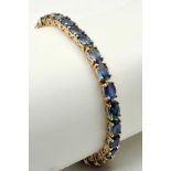 A Spellbinding 9K Yellow Gold Sapphire Tennis Bracelet. Oval cut sapphires. 19cm. 10.45g. Ref: