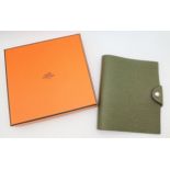 An Hermès Olive Green Togo Leather Ulysse Notepad Cover. Olive green leather exterior with silver-