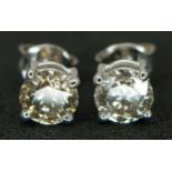 A Pair of 18K White Gold Diamond Stud Earrings. Champagne tinted round brilliant cut diamonds c. 1.