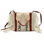 A Chloé Woody Fringed Tote Bag. Cream woven textile exterior with long fringed sides, tan leather