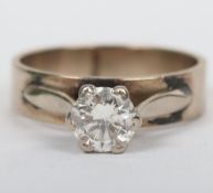 An unmarked substantial gold solitaire ring, the single stone on thick band, probably 18ct white