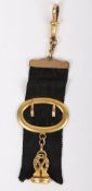 A 15ct chain and clasp holding a black ribbon and gilt fob seal,