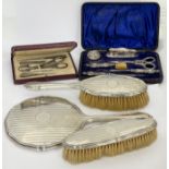 A silver-mounted dressing table set, comprising a hand mirror and two brushes, William Devenport,