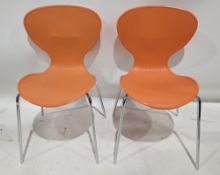 Eight orange stackable cafe bistro chairs with polypropylene shell seats with ribbed backs, on