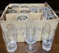 Collection of branded drinking glasses including Pilsner Urquell lager glasses, Smirnoff tumblers,