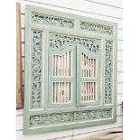 South east Asian painted wooden shutter mirror, having pierced foliate scroll frame and two