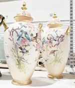 Pair of early 20th century blush ivory lidded urns decorated with birds, butterflies and flowers,