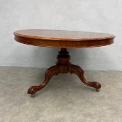 A C.1900 mahogany dining table having a circular tilt-top raised on a turned stem on carved and