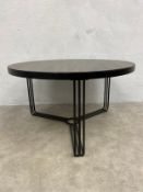 A contemporary Finn coffee table with circular faux wood top raised on bent matt black metal