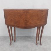 A 19th century mahogany drop-leaf side table having a quarter-veneered and lobed top with gate-leg