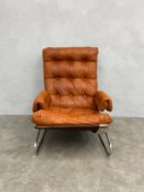 A 1970s Norwegian tan leather and chrome lounge chair with deep buttoned back and seat raised on