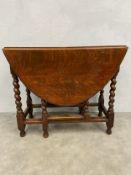 A 19th century oak drop-leaf dining table having an oval top raised on stretchered barleytwist