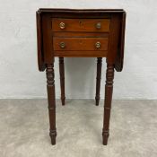 A 19th century mahogany Pembroke work table with drop flaps raised on ring turned tapering supports.