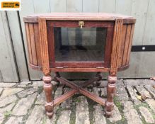 A 20th century oak display or side cabinet with an oval top over two opposing glazed cabinet doors