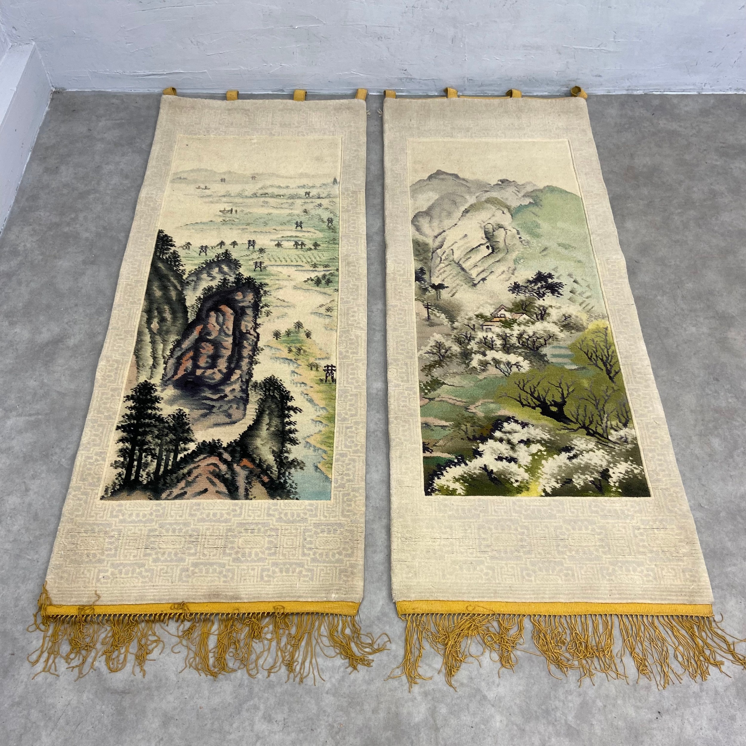 A pair of vintage Chinese part silk wall hanging rugs each with central vignette depicting a