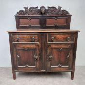An early 20th century oak Jacobean style side cabinet with carved back above base fitted with