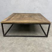 A contemporary coffee table with square reclaimed parquet wood top raised on a square tubular