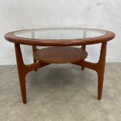 A mid century teak coffee table with inset plate glass top on shaped supports united by undertier.