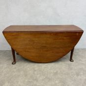 A Georgian mahogany drop leaf table with oval top raised on straight circular section supports on