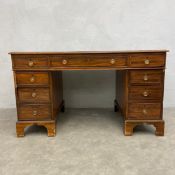A Georgian mahogany twin pedestal desk with green leather top over an arrangement of nine figured