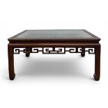 A mid to late 20th century Chinese coffee table with square glass inset top over the carved openwork