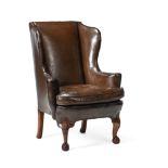 A CARVED WALNUT AND LEATHER UPHOLSTERED WING ARMCHAIR, BY HOWARD & SONS, EARLY 20TH CENTURY