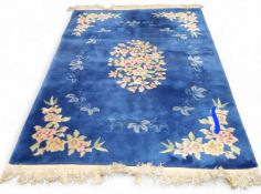 A Chinese woollen rug, with central floral cartouche on a blue ground, 210cm x 140cm, c.1930