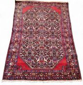 A Persian Sarouk woollen rug, with stylised flowers and scrolls in red, blue and cream, 147cm x
