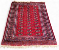 An Afghan/Pakistani Bokhara woollen rug with repeating octagonal gols on a red ground, 176cm x