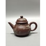 A treasured antique purple clay teapot, featuring a small inscription on the bottom reading "Made by