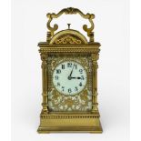 A brass cased carriage clock, shaped bale handle, column mounted, pierced dial plate with dragons,