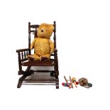 A mid-20th century teddy bear together with a child's rocking chair and smaller toys.