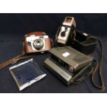 Three vintage cameras including a Bell & Howell, Polaroid with pack of film and AGFA cased camera