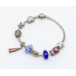 A silver Pandora charm bracelet, with various charms including enamel light house, stone set