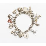 A vintage silver charm bracelet, comprising a curb link with padlock clasp, width approx 7mm, length