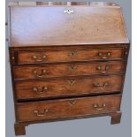 A George III oak bureau with dropdown writing surface to reveal stationary compartments and four