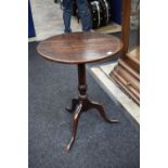 A George III tilt top table with turned stem, plank top standing on tripod legs along with a fixed