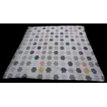 A vintage quilt for a double bed, white background with hand-stitched patchwork motifs of lilac/