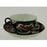 A Worcester tea cup and saucer, c.1760-65, painted with panels of colourful exotic birds within gilt