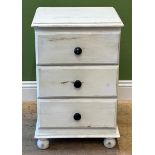 A white painted pine bedside table with three draws with ebonised knobs, on ball feet, 71cmH