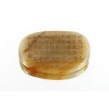 A Chinese jade tablet of oval form, decorated with script, 7.3cm long