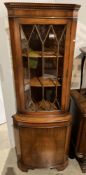 Mahogany bow front freestanding corner cupboard with single glazed door over lower door,